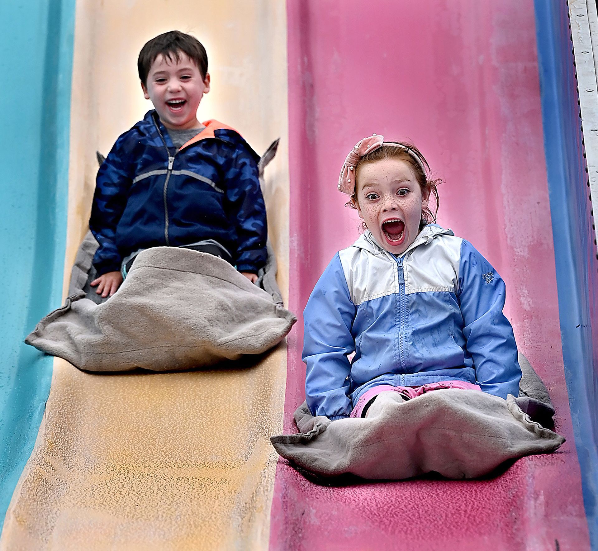 Arianna Cicio, 6, of Bellingham, right, and her brother Anthony, 4, zoom down the Fun Slide at the Holliston Lions Club's carnival at Holliston High School, Thursday July 8, 2021.