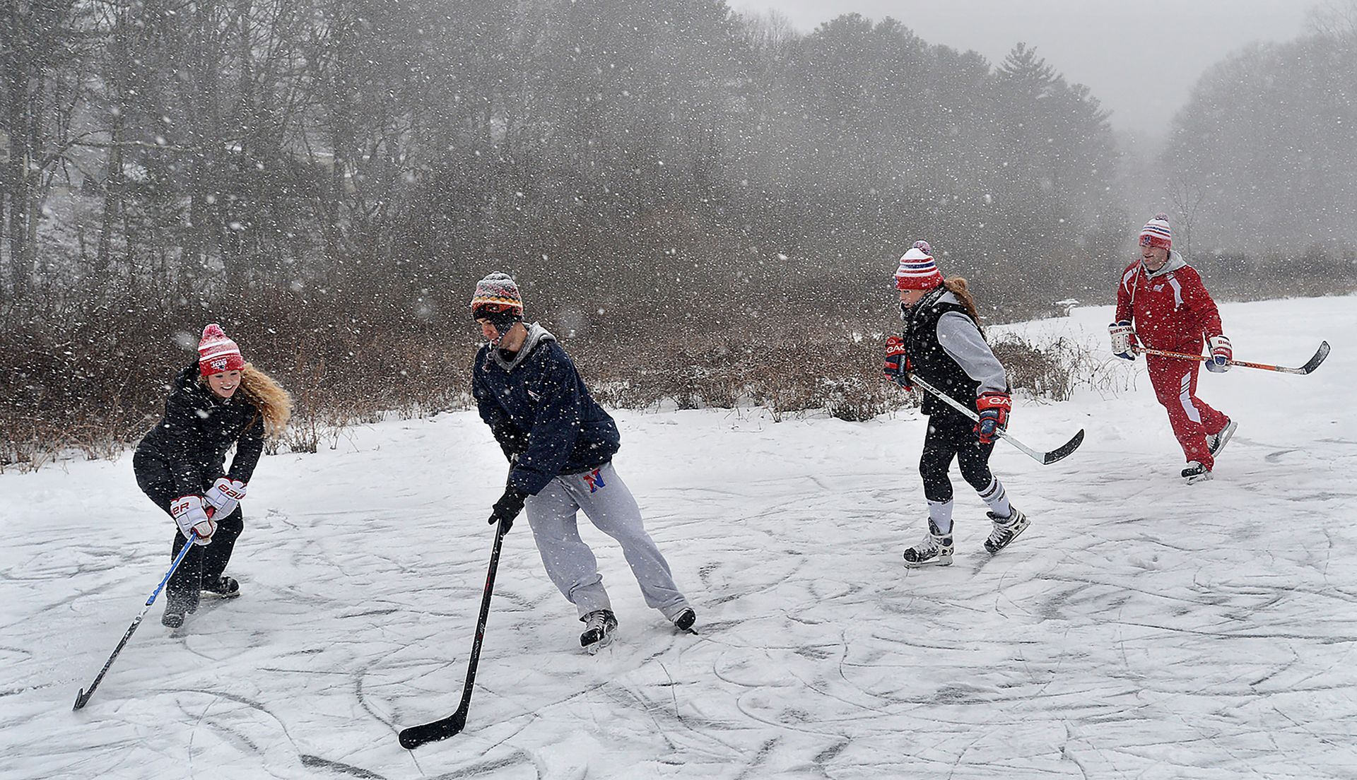 As the first major snowstorm of the season moved in, Katelyn Galvin, 23, left, Tyler Vlass, 26, Gina Zambarano, 24, and Mike Zambarano, 26, continued to play a friendly round of pond hockey at Jennings Pond in Natick , Saturday, January 23, 2016