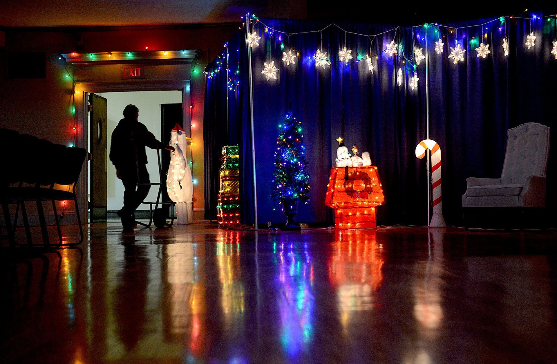 Framingham facilities worker Rob Klein is framed in a doorway at darkened Nevins Hall as he moves a decorations in preparation for a Holiday Pops Concert, Dec. 12, 2014.