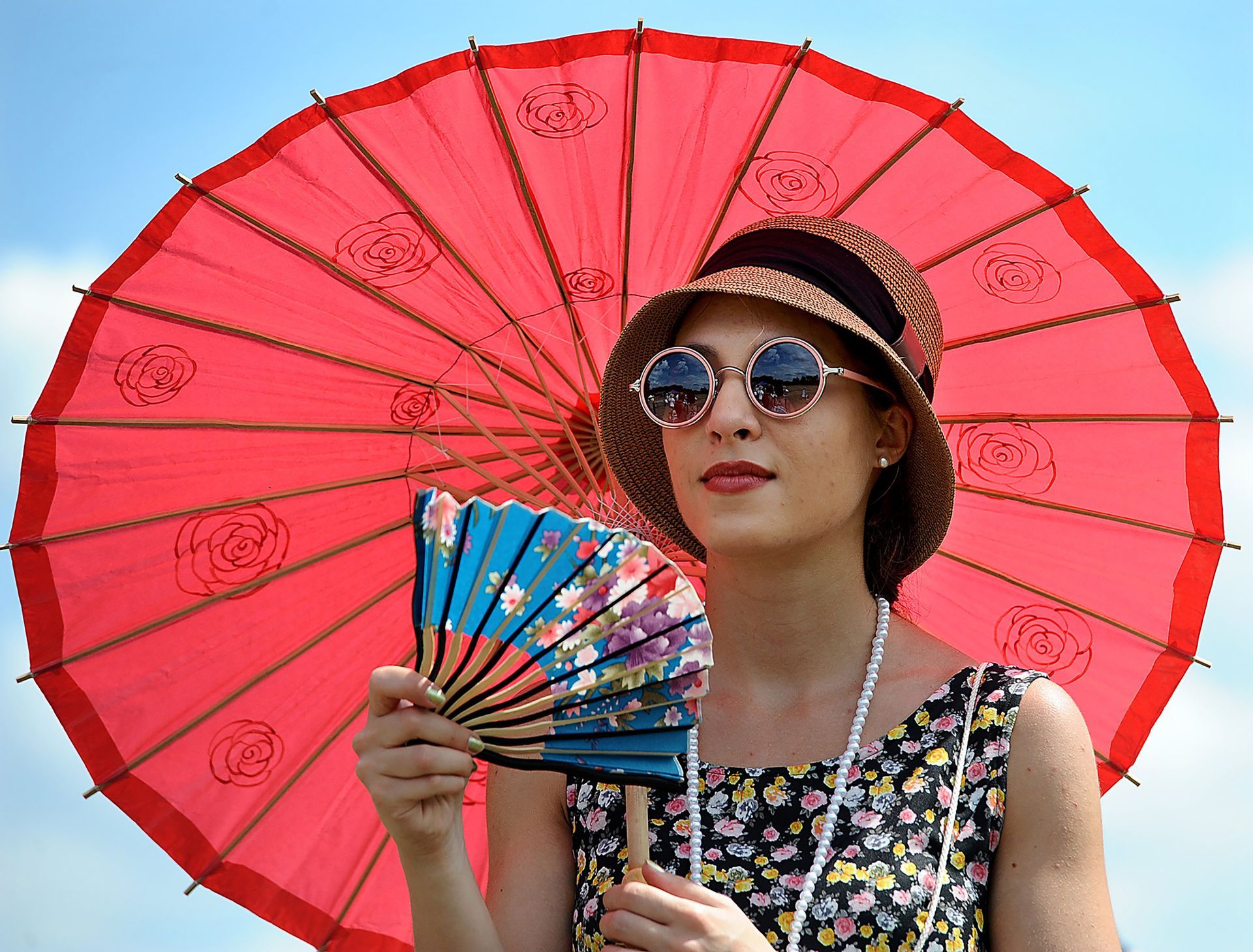 A parasol and fan keep Katie Burke of Melrose cool as she watches the Race of the Century, an annual period affair featuring competition between vehicles of different technologies and eras at the Collings Foundation in Stow Saturday, July 30, 2016.