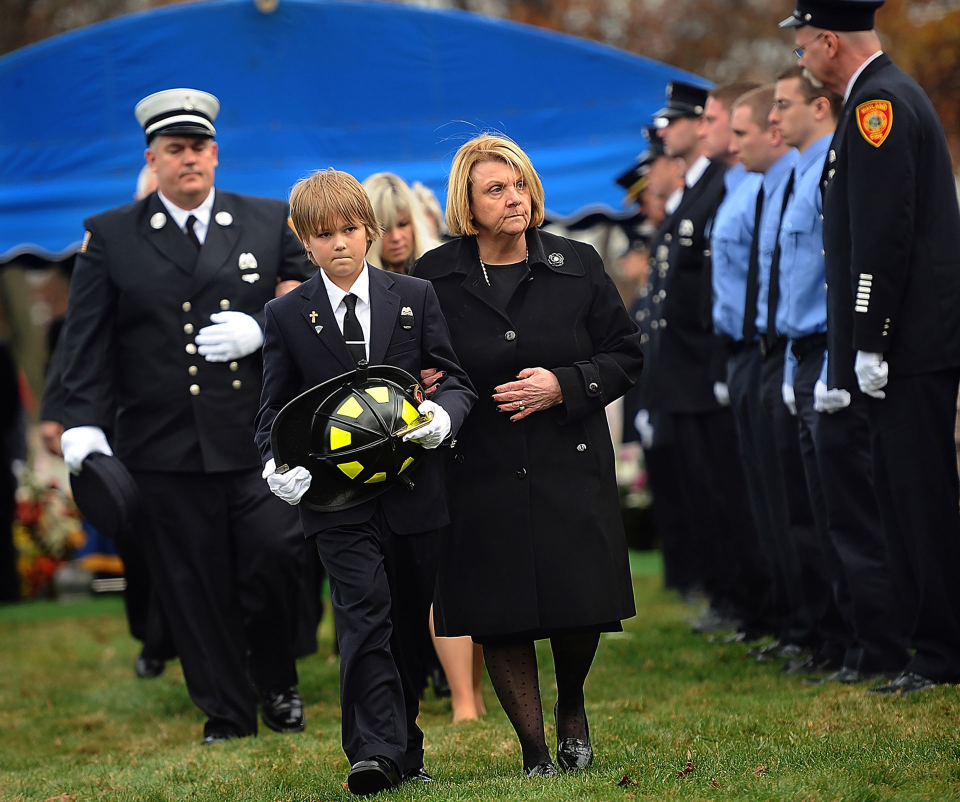 Christian Donohue, 10, of Natick, stepson of Wayland firefighter Peter Regan, carries his father's helmet following Regan's burial service at St. Patrick's Cemetery in Natick, Nov. 10, 2010. Regan, 43, died from injuries sustained in an accident at home.