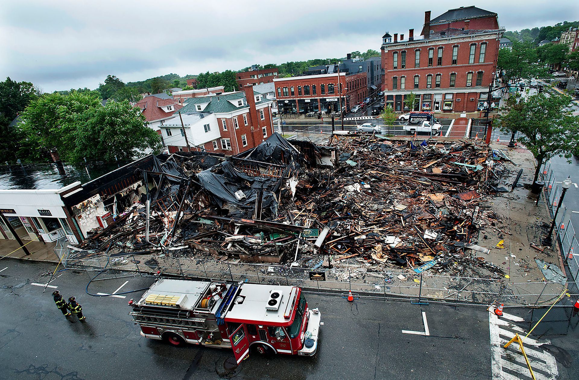 Natick firefighters stand by to put out hot spots as a downtown Natick business block lies in ruins on Tuesday, July 23, 2019 after an eight-alarm fire the previous nigh