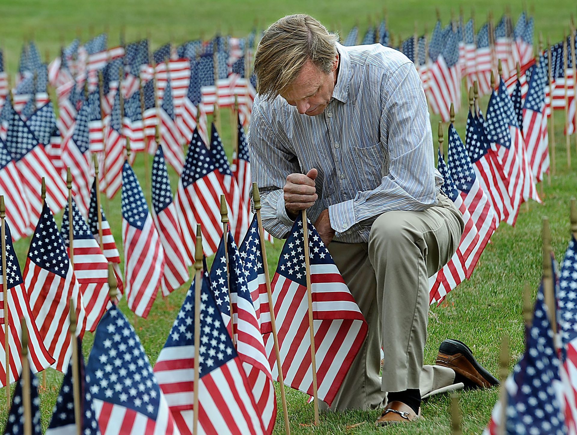 Weston resident Peter Keating says a prayer after helping to place 3,000 flags on the Weston Town Green in memory of the victims of the Sept. 11, 2001 terrorist attacks, on Sept. 11, 2014.