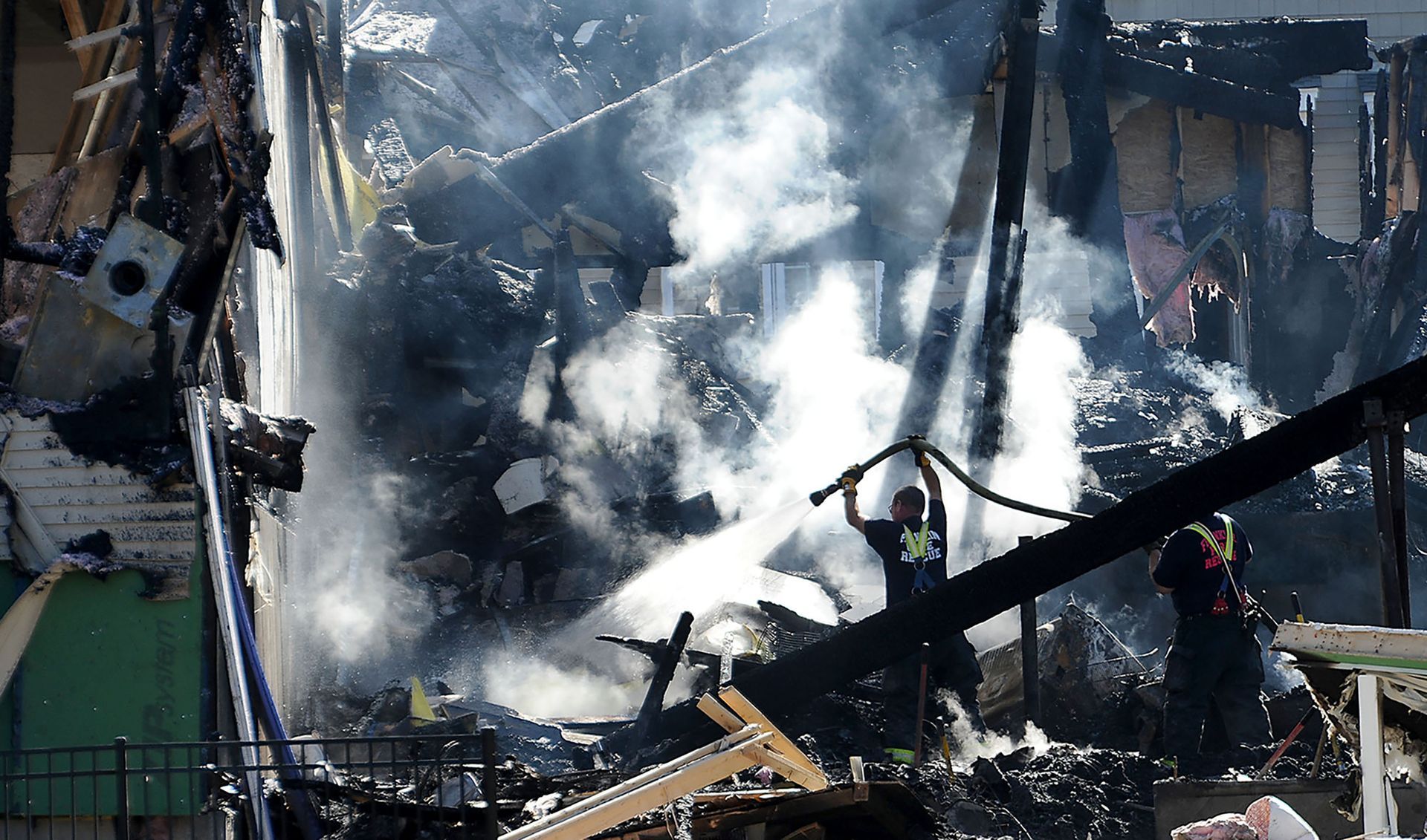 Firefighters put water on the smoldering ruins of a condo at The Villages on Oak Hill in Franklin, hours after an early-morning explosion and fire, on Saturday, October 10, 2015. Nancy and Richard Brown, both 66, the owners of the condo unit, died in the explosion.