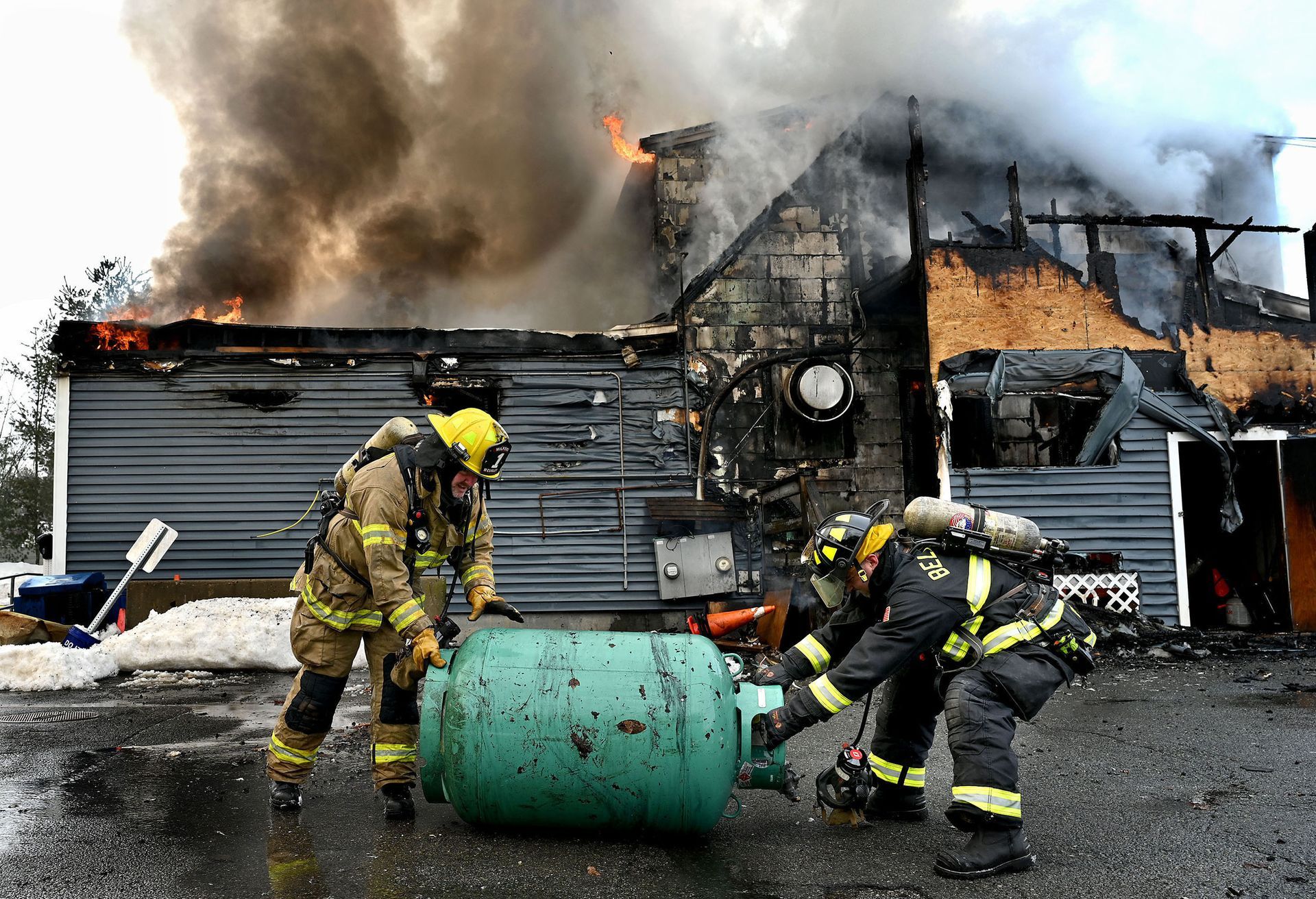 Firefighters roll a fuel tank away from a fire at The Tradesman, a well-known restaurant and bar on West Street in Milford, Feb. 13, 2021. Despite the efforts of firefighters from multiple communities, the structure was a total loss.