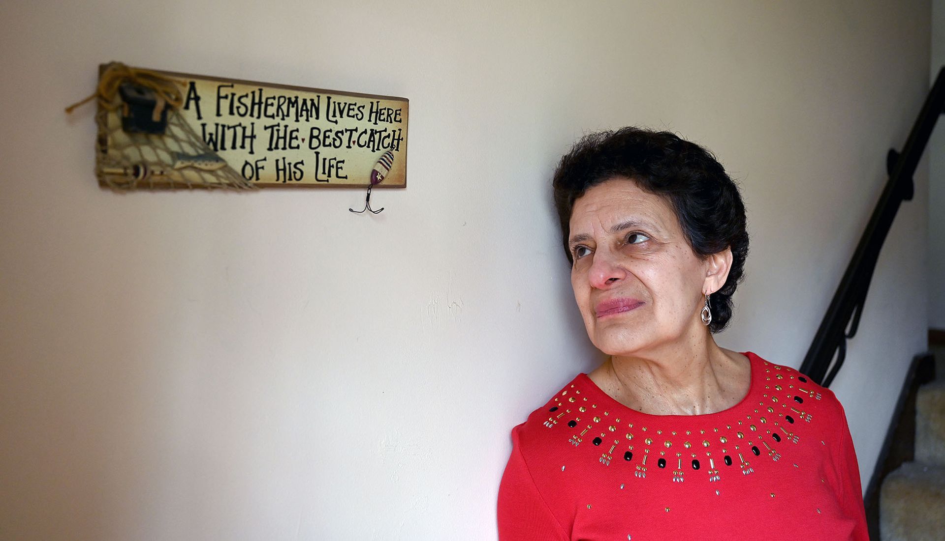 Sheila Courchaine of Marborough, who lost her husband Armand Courchaine to the coronavirus, gazes at sign where her husband, a lifelong fly fisherman, calls her the