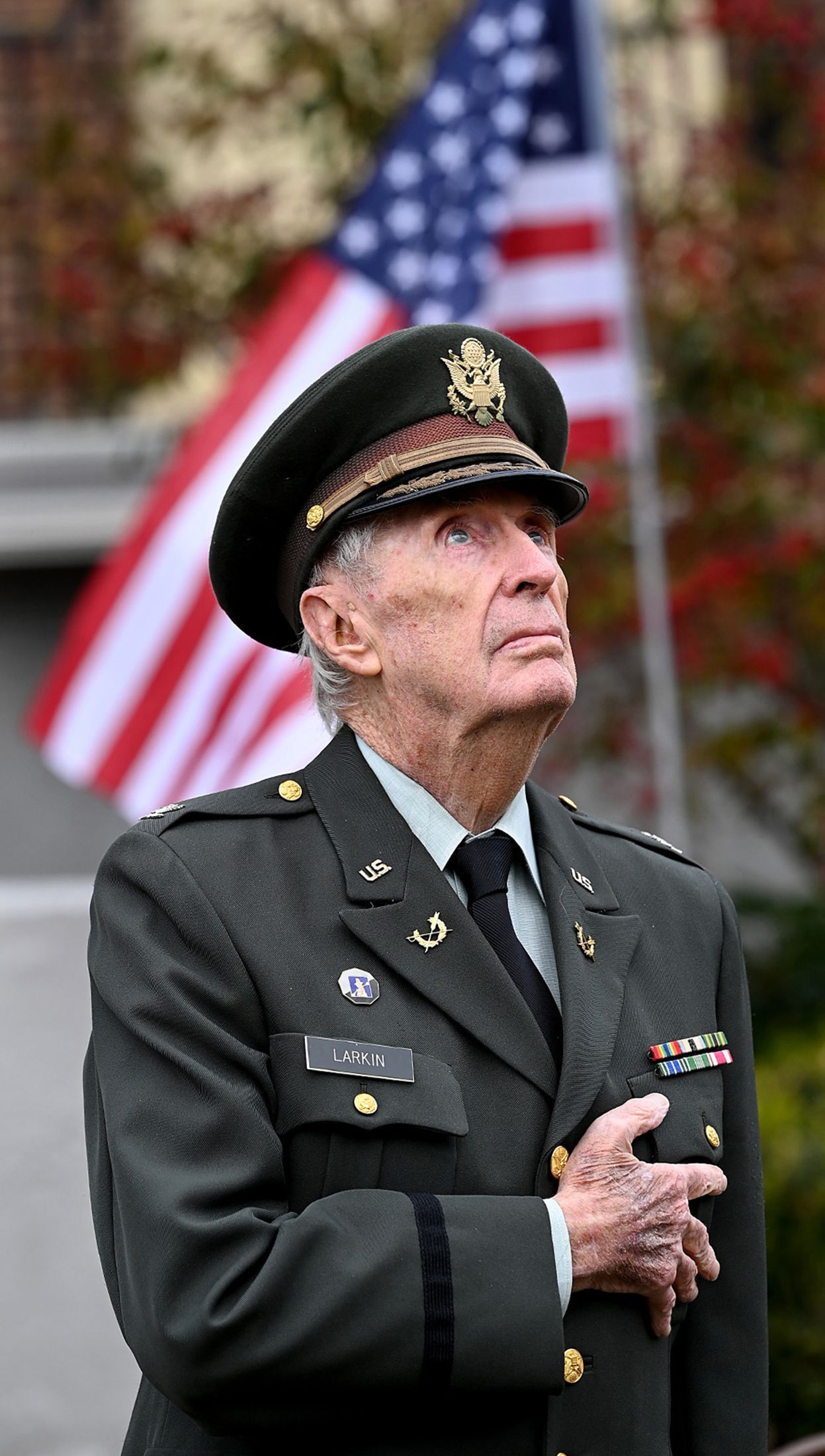 Retired U.S. Army Col. Francis Larkin, 89, stands at attention as an echo taps is played during a Veterans Day ceremony at the Hopedale Community House, Nov. 10, 2021.