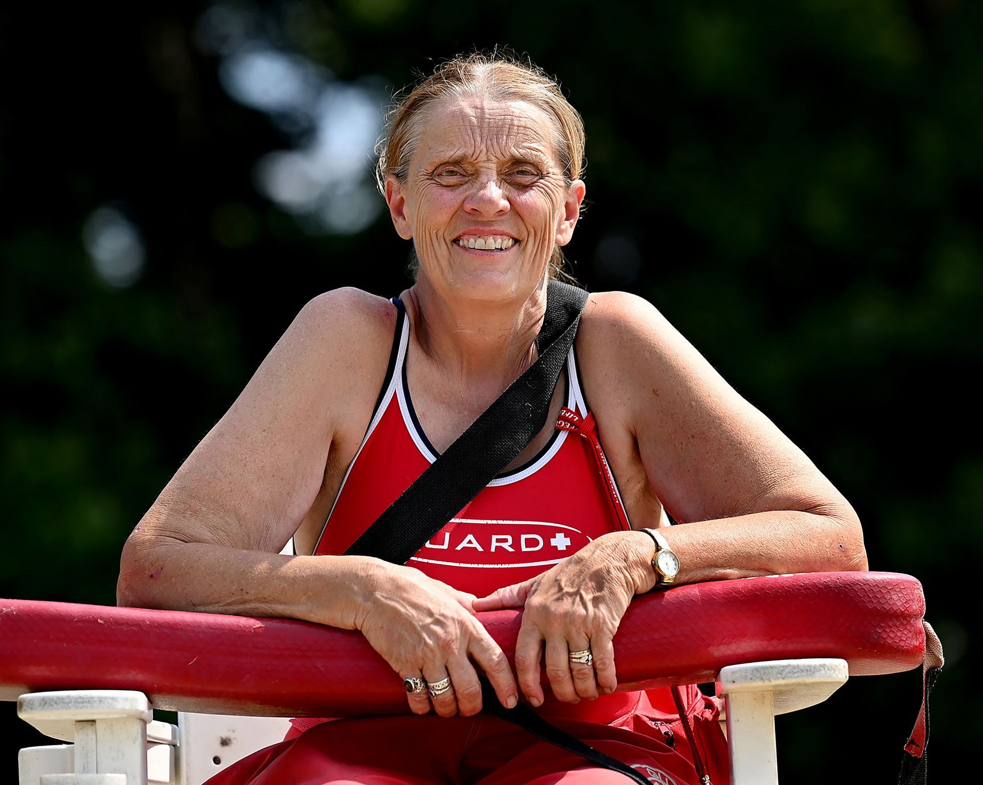 Lifeguard Heidi Sardina, 65, sits on a lifeguard chair on the last day of the season at Framingham's Learned Pond Beach, August 12, 2021. The retired Waltham middle school teacher has been lifeguarding since 1972.