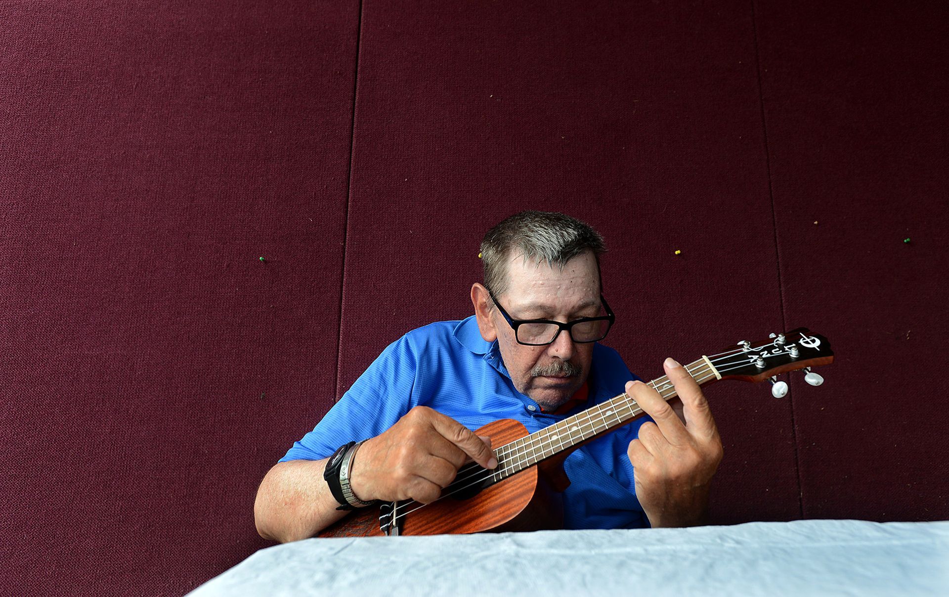 David Howland, 67, a resident of a group home in Marlborough, finds a quiet corner to strum on his ukulele during the Thrive Support and Advocacy's Fun Fest Saturday, July 15, 2017 at the Hudson Elks.