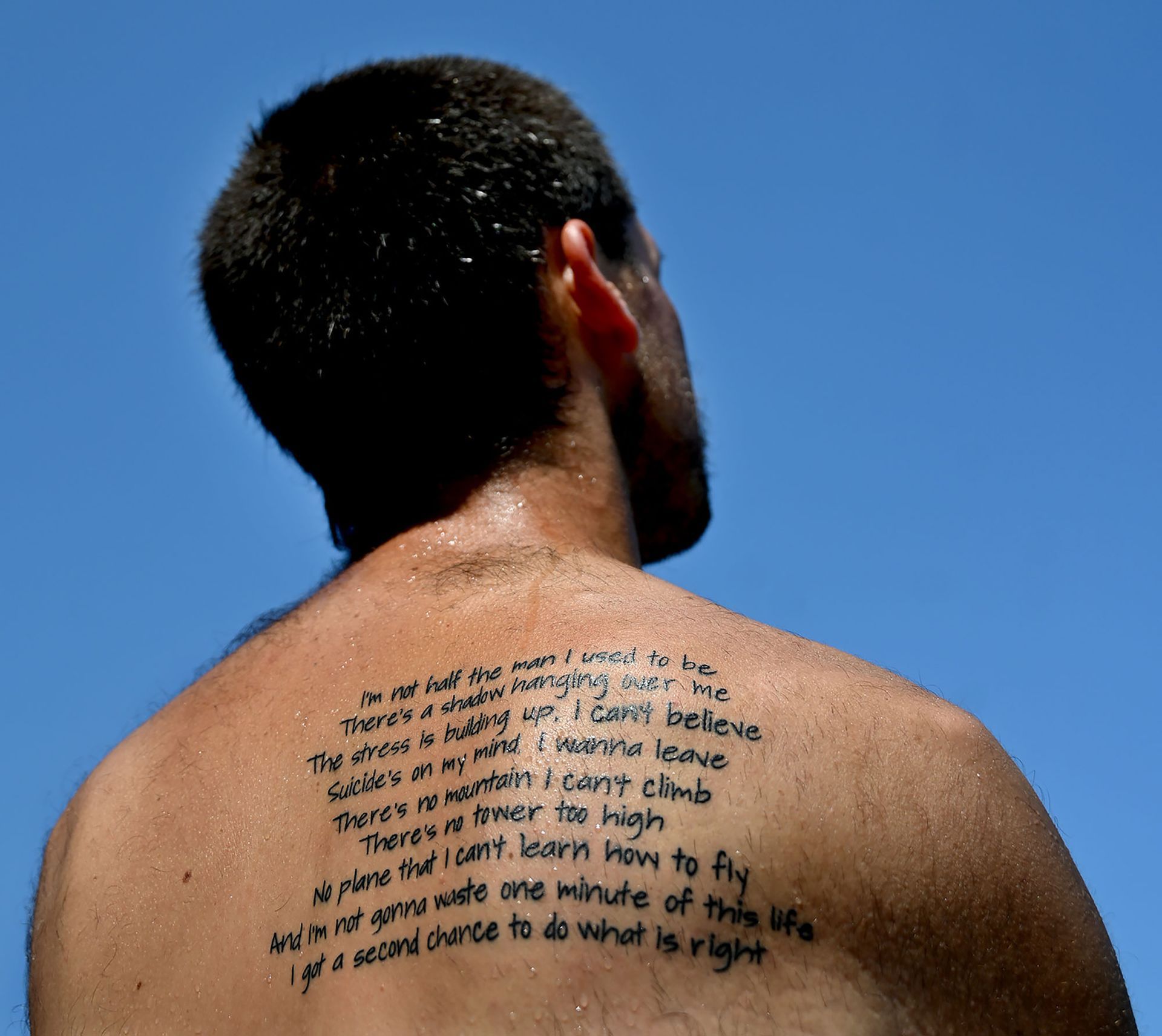 Dylan Abbott, 28, a former drugs and alcohol addict who had a few brushes with the law in his youth, shows tattoos on his back on Friday, July 26, before competing in a triathlon to raise money for improved health care, including addiction treatment. T