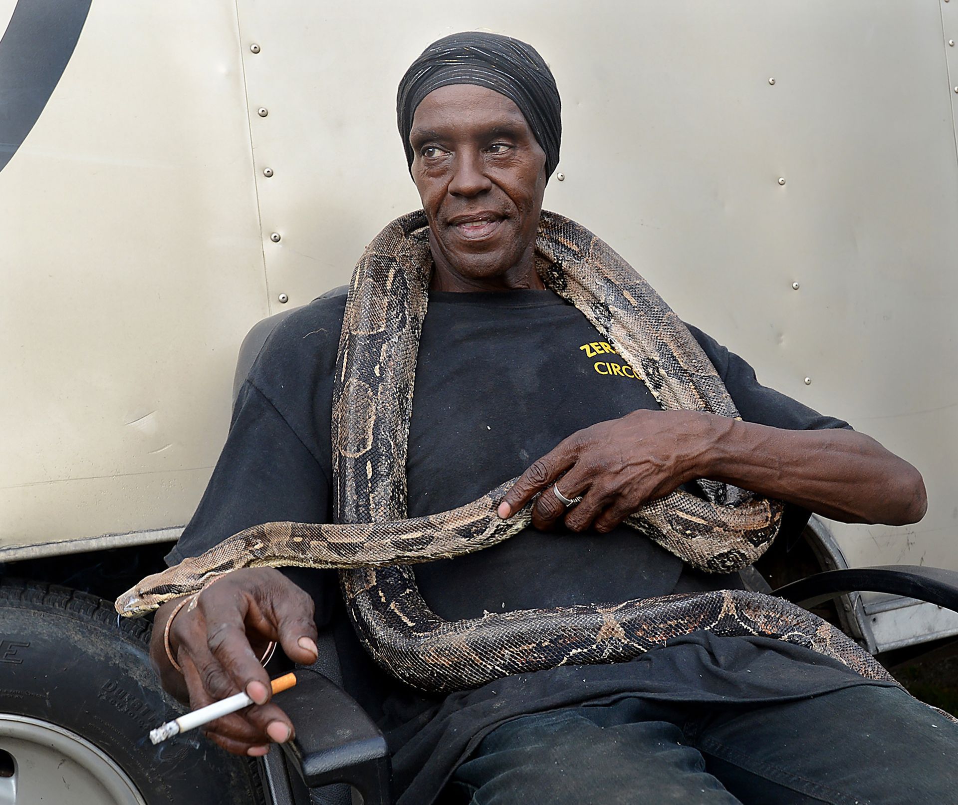 Circus worker Christian Mitchell relaxes with Cindy, a Columbian red-tailed boa, during a break at the Zerbini Family Circus show in Mendon Thursday night, July 28, 2016.