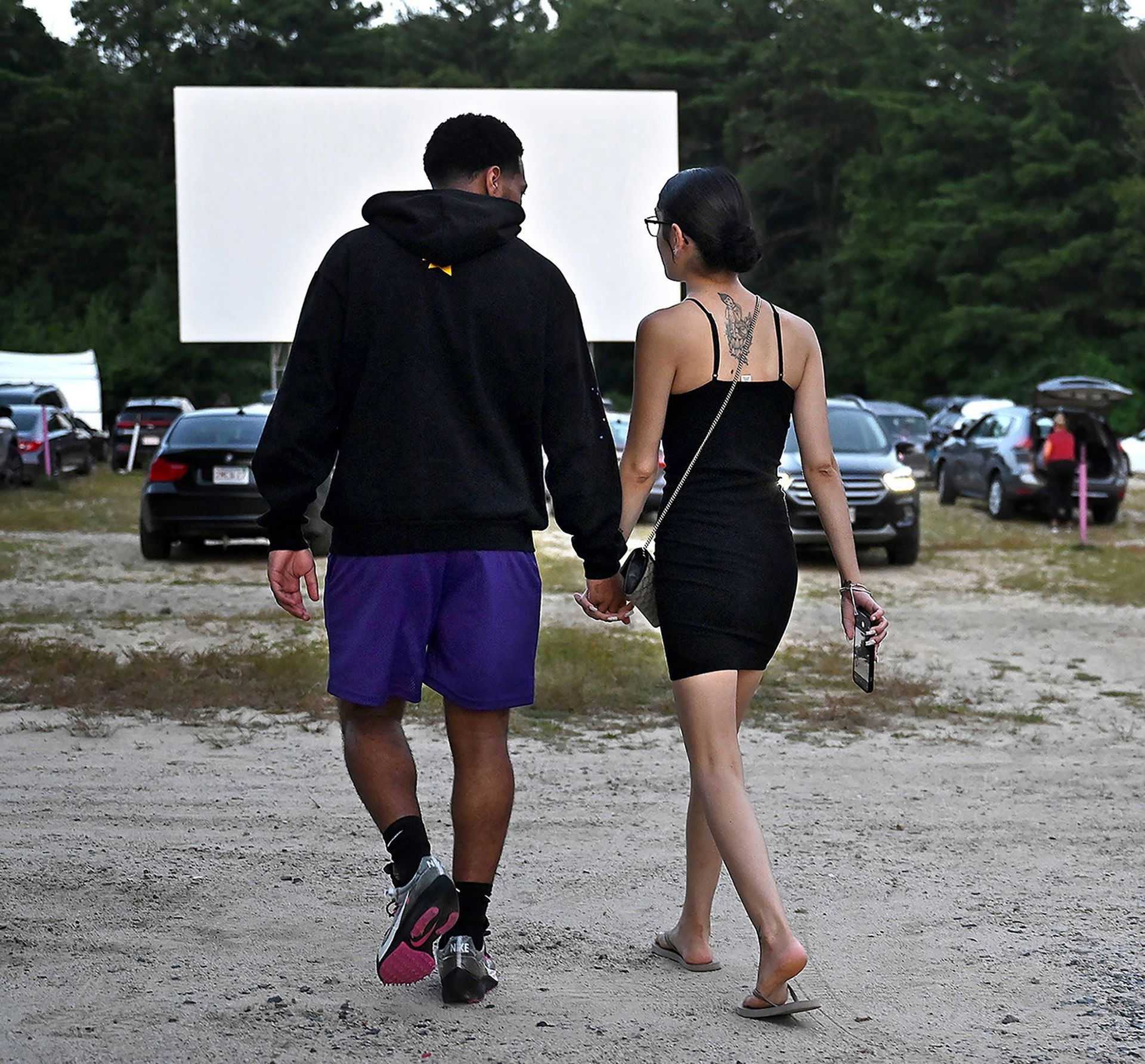 A couple holds hands as they make their way to the car to watch an opening night showing of the the cowboys and aliens monster movie
