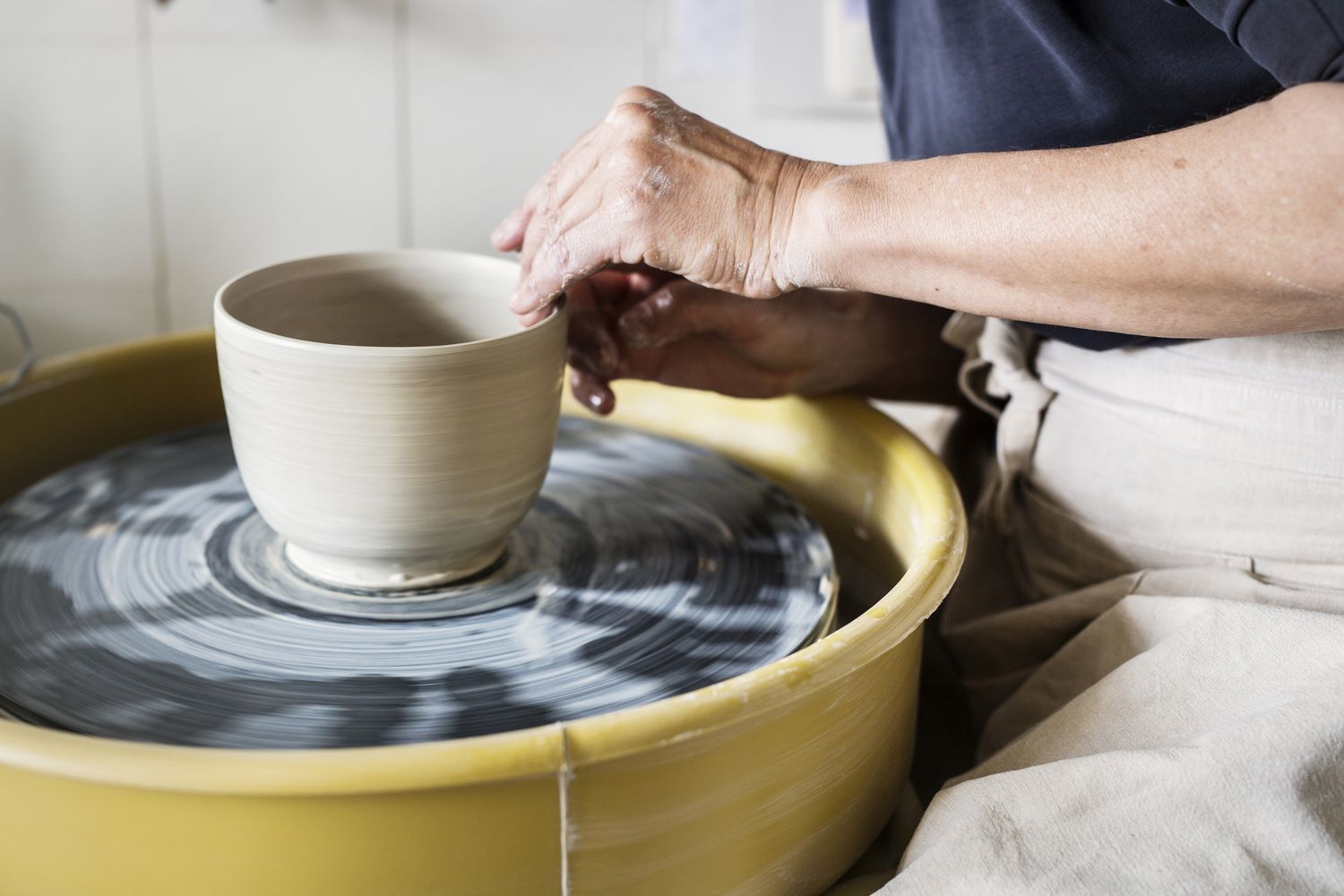 A person is making a bowl on a pottery wheel.