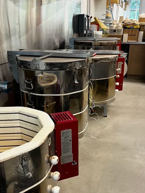 A row of pottery kilns are lined up in a room.