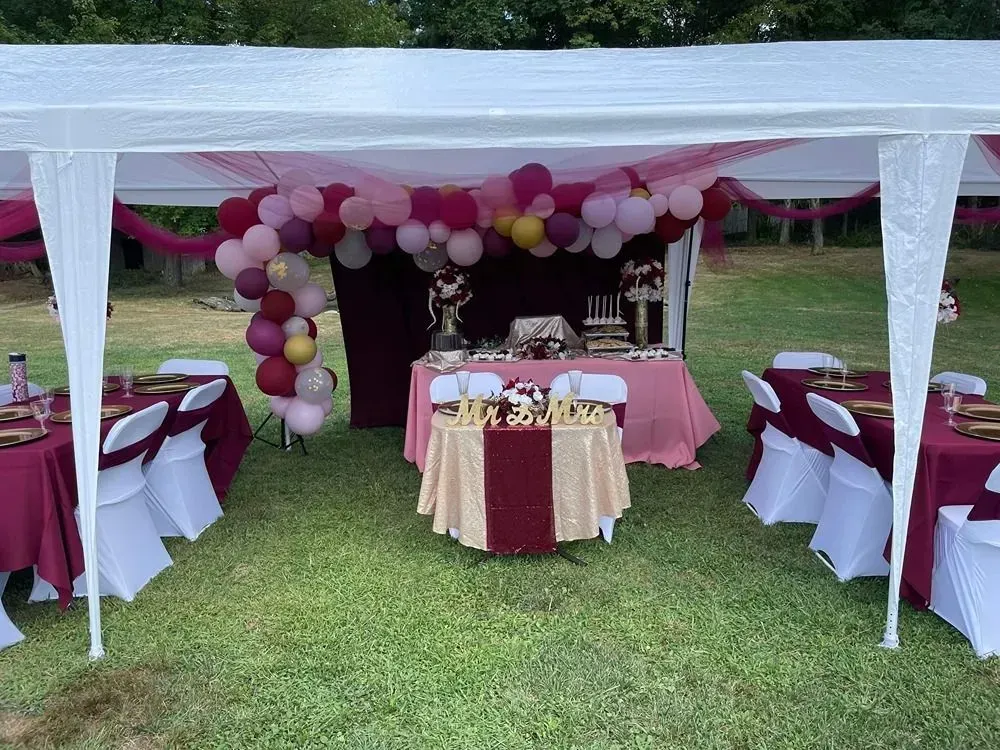 a table and chairs under a tent with balloons on it .