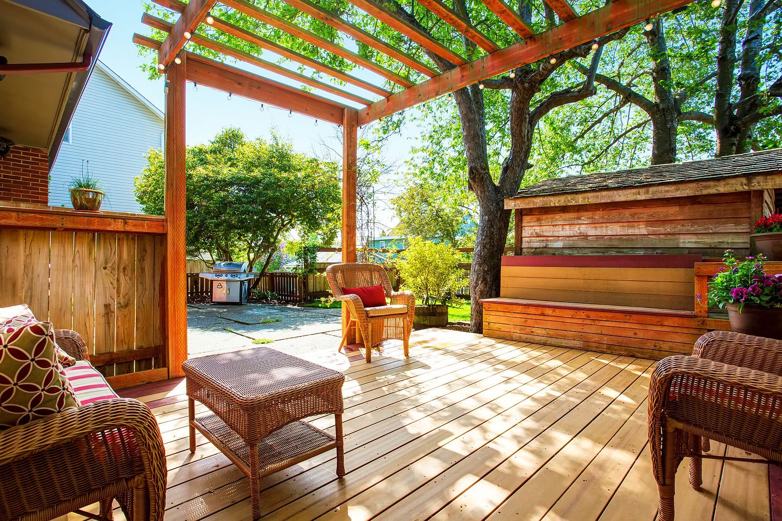 A wooden deck with wicker furniture and a pergola.