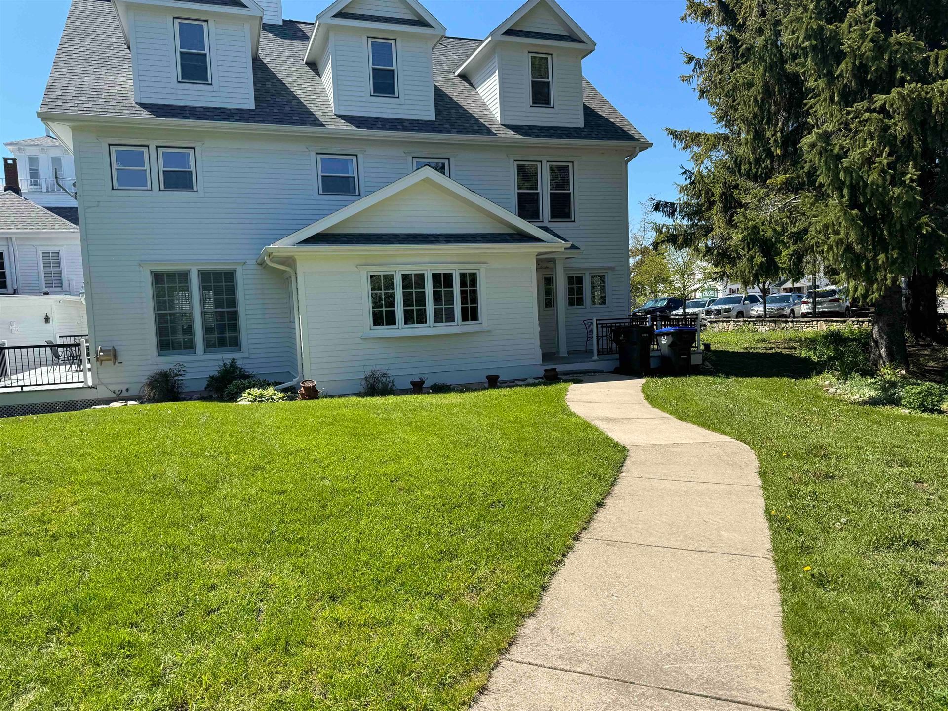 A white house with a concrete walkway leading to it.