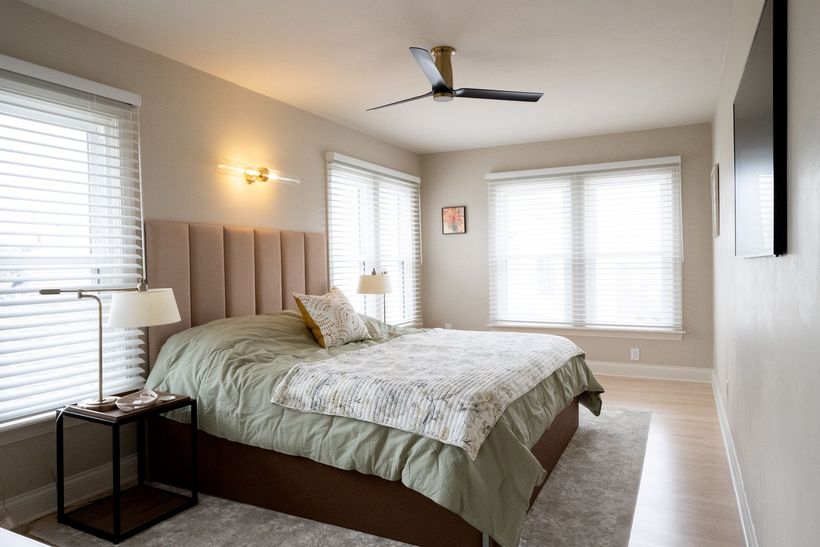 A bedroom with a king size bed , dresser , nightstand , chair and rug.