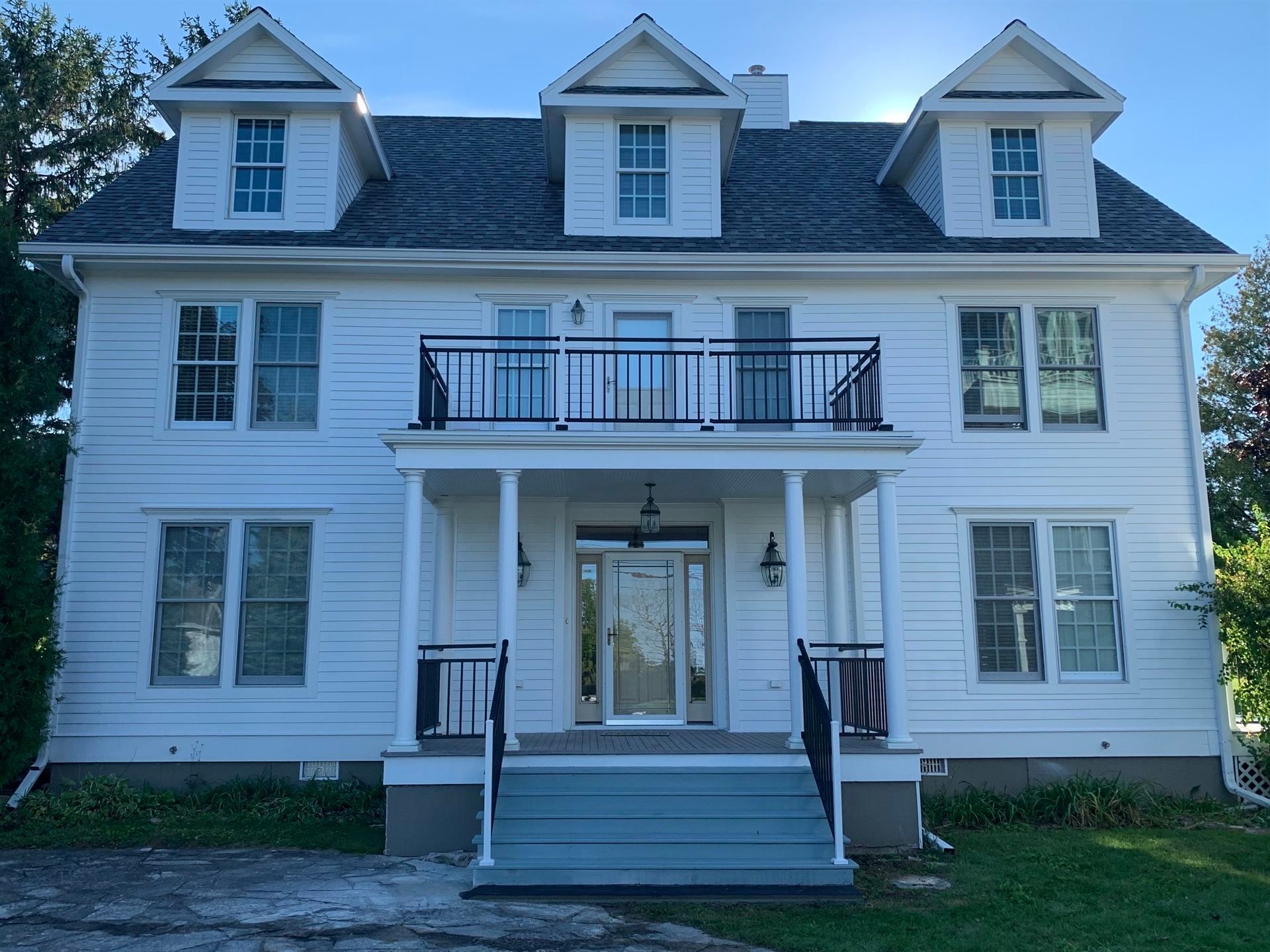 A large white house with a balcony and stairs