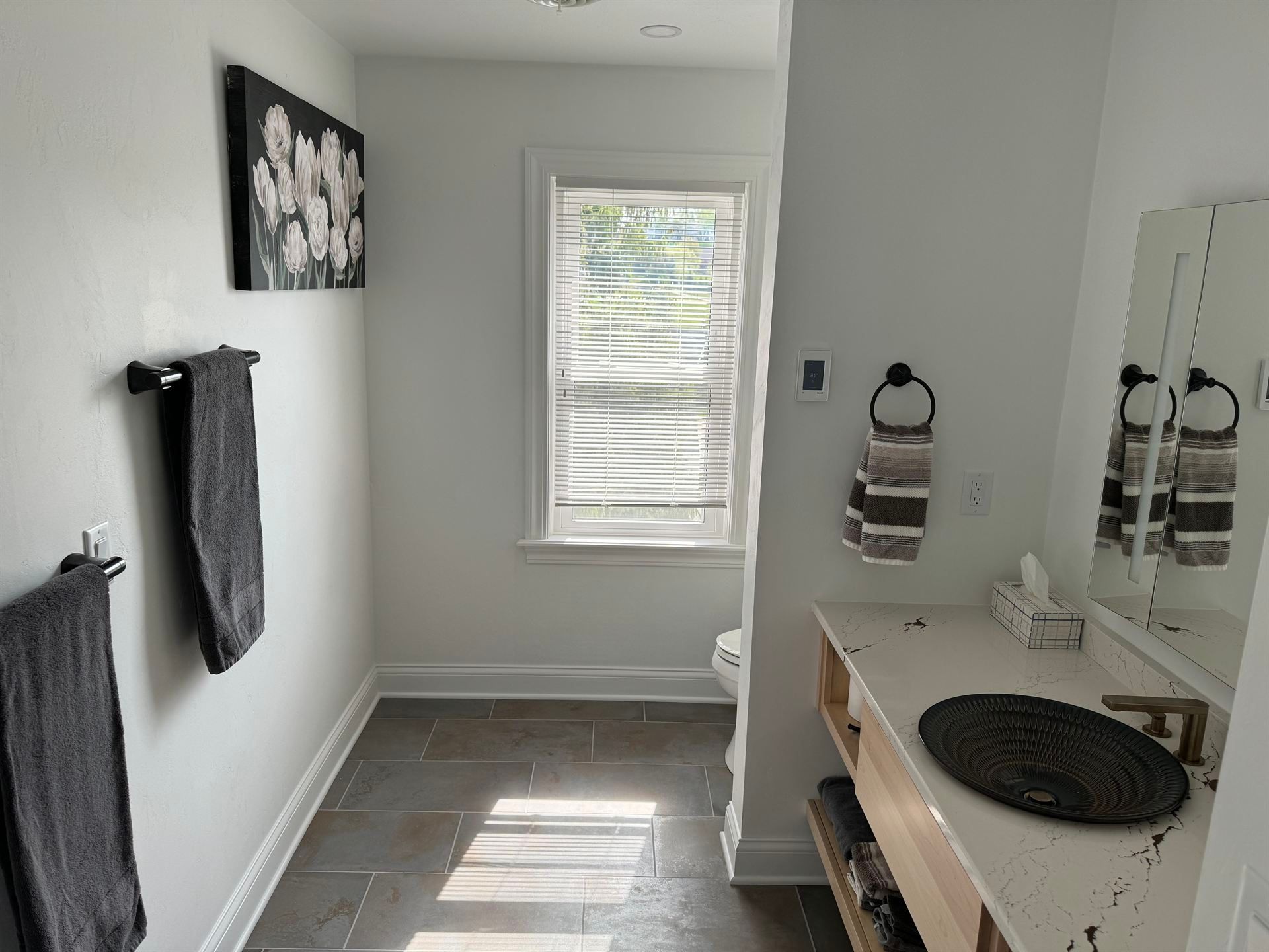 A bathroom with a sink , mirror and window.
