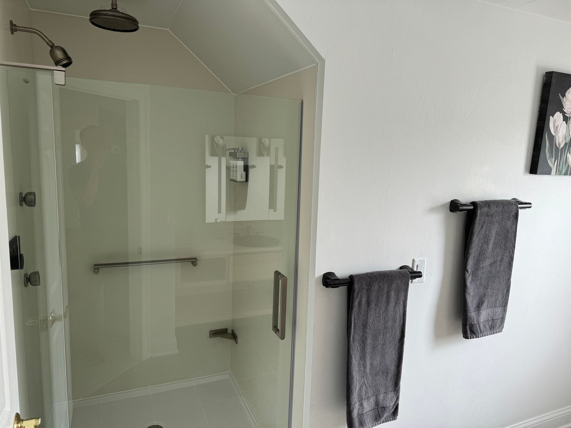 A bathroom with a shower and two towels hanging on the wall.