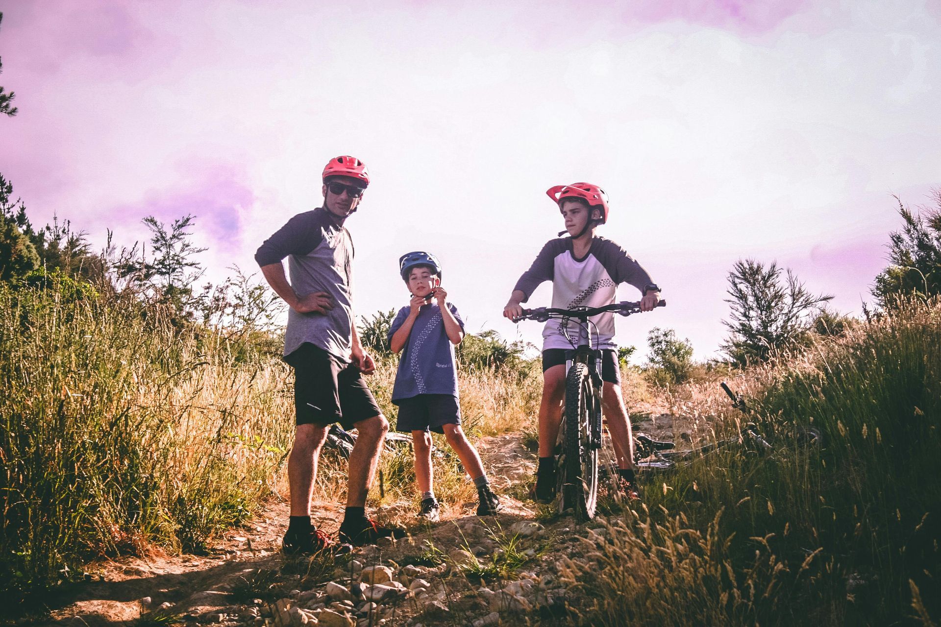 A man and two children are standing next to each other on a dirt road.