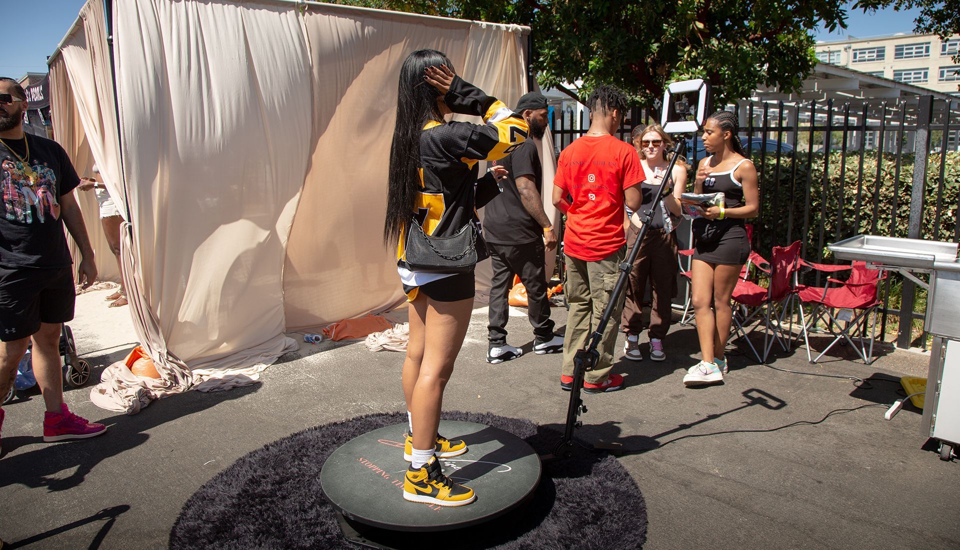 Person on a rotating platform outdoors, posing. Others observe around them.