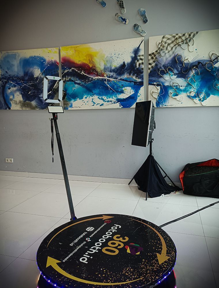 A 360 photo booth with equipment set up in front of colorful artwork.