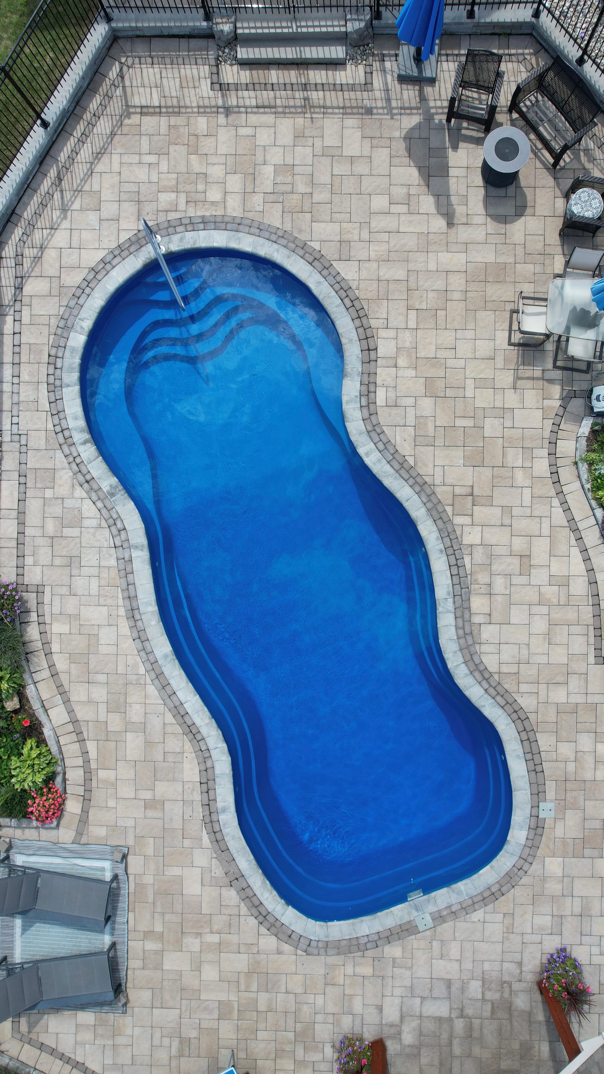 An aerial view of a large blue swimming pool in a backyard.