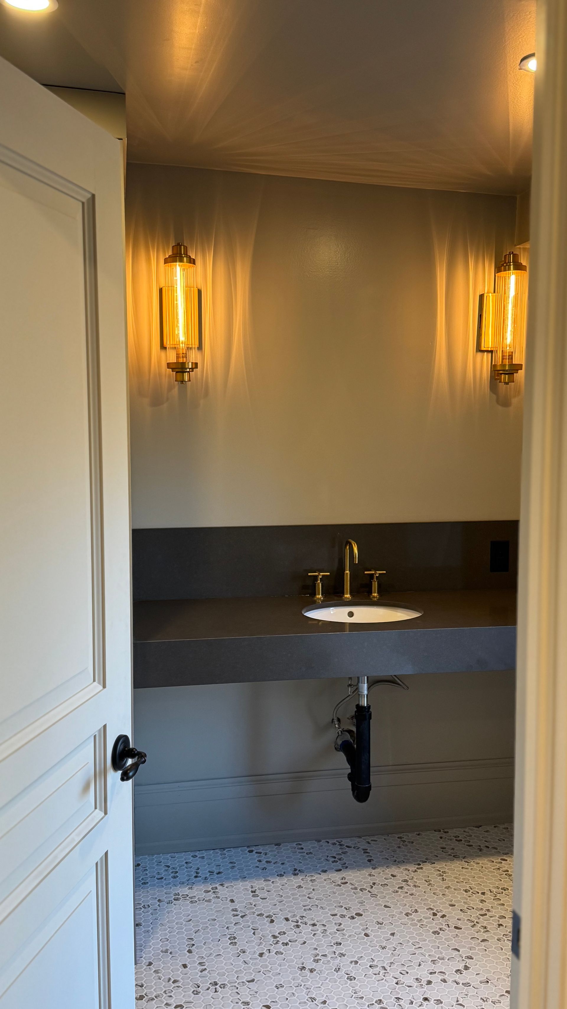 A bathroom with a sink and two lights on the wall.