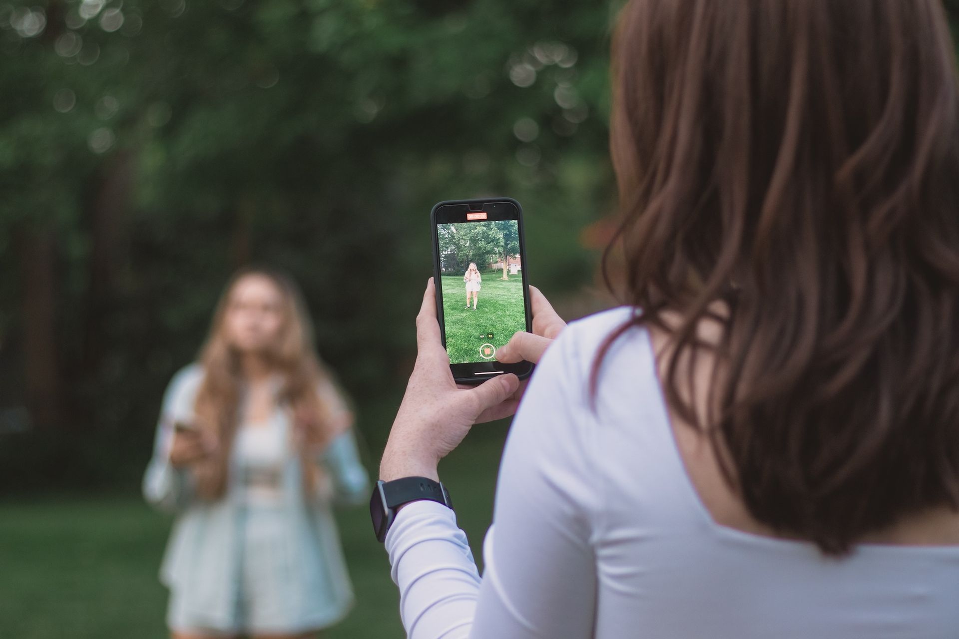 A woman is taking a picture of another woman with a cell phone.