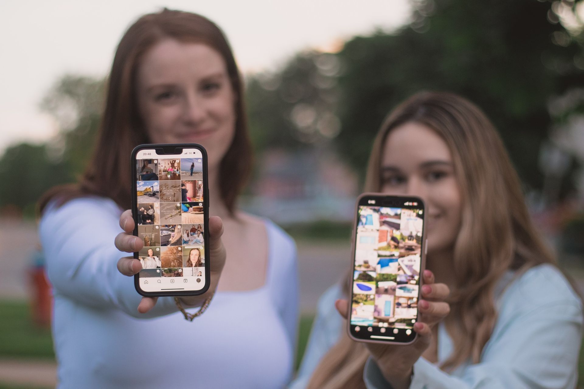 Two young women are holding up their cell phones.