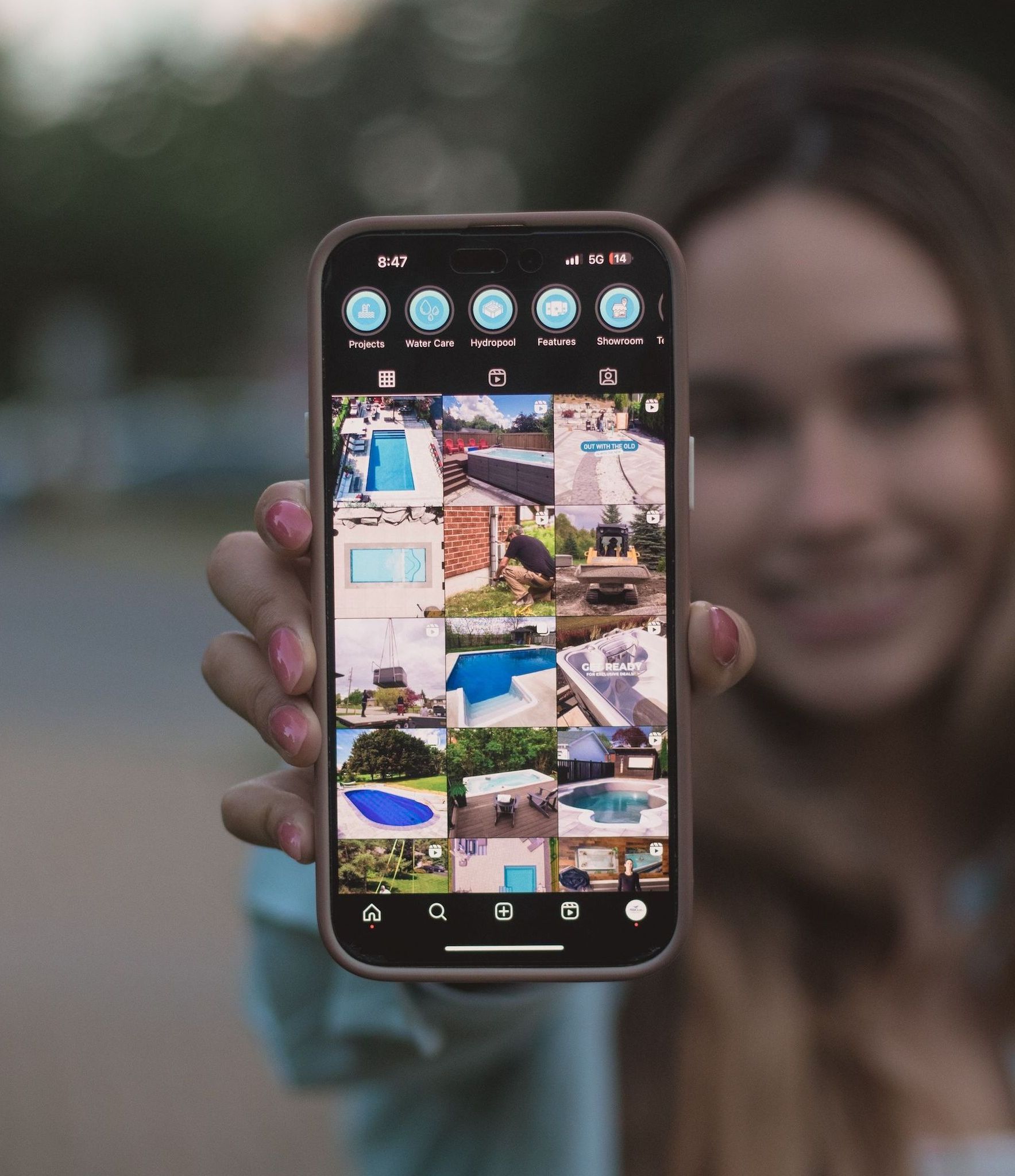 A woman is holding a cell phone with a bunch of pictures on it.