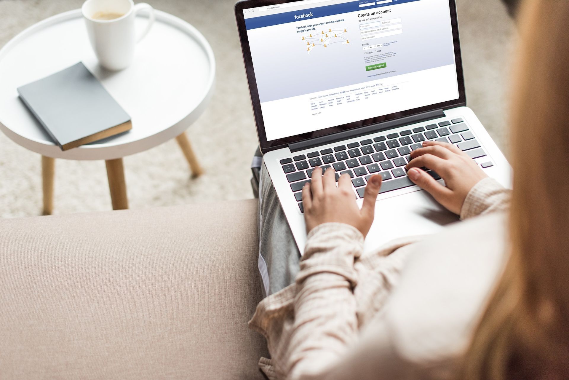 A woman is sitting on a couch using a laptop computer.