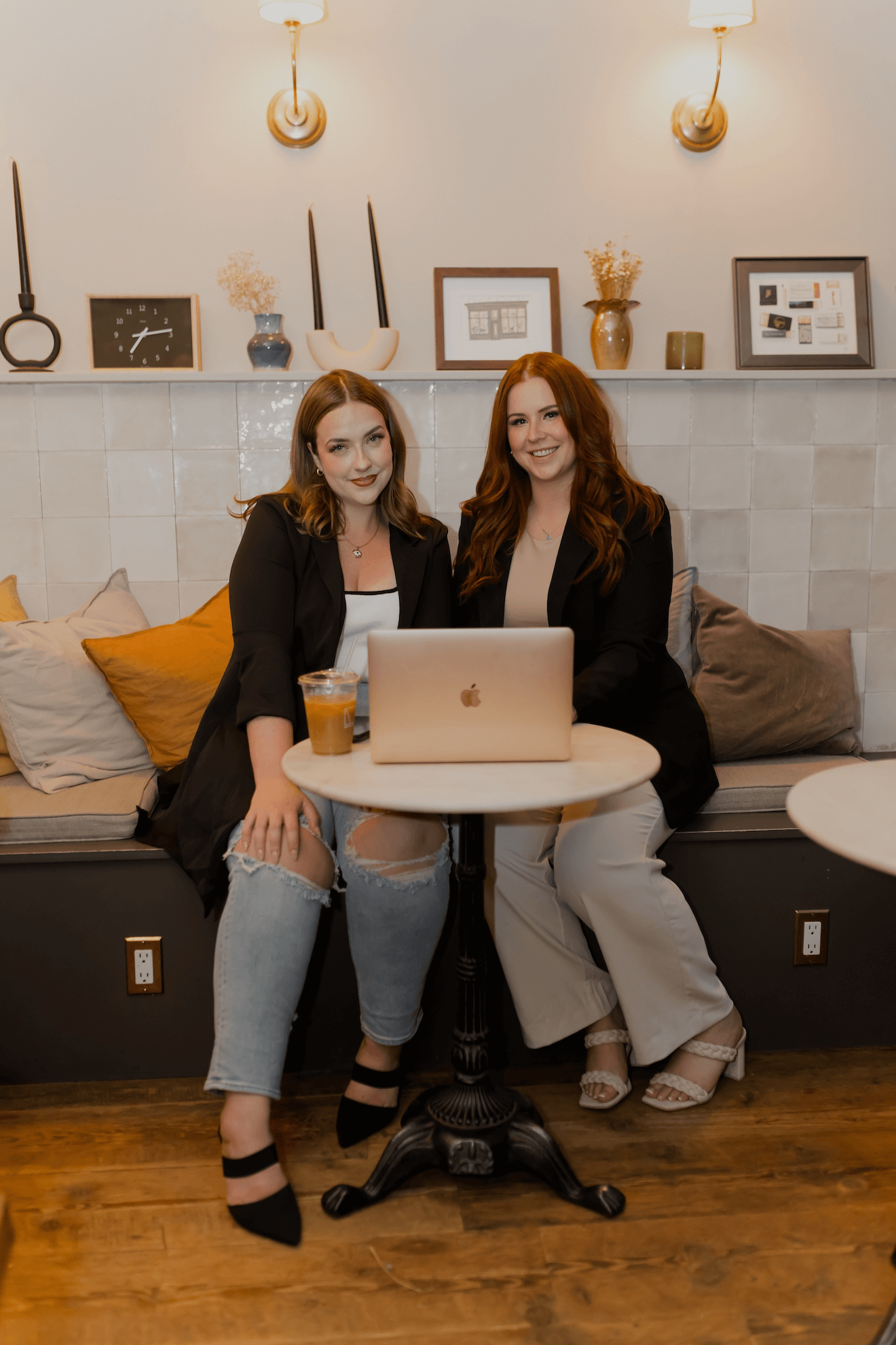 Two women are sitting at a table with a laptop.