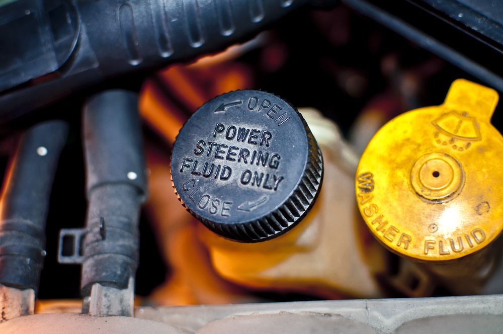 Black cap with "POWER STEERING FLUID ONLY" label in engine bay, beside a yellow washer fluid cap — All Mechanical Services in South Murwillumbah, NSW