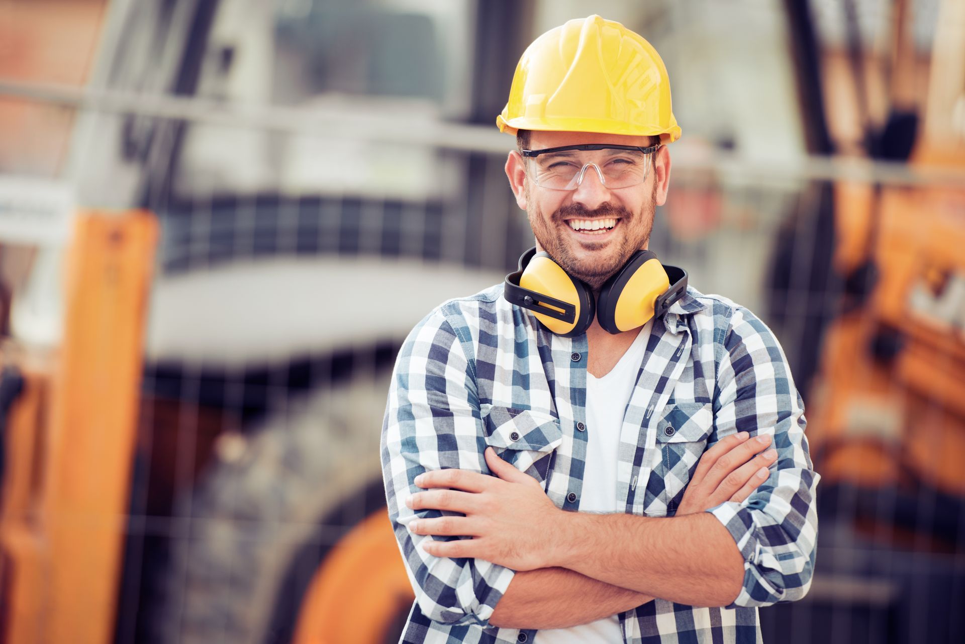 Construction worker wearing a hard hat and hearing protection at a job site.