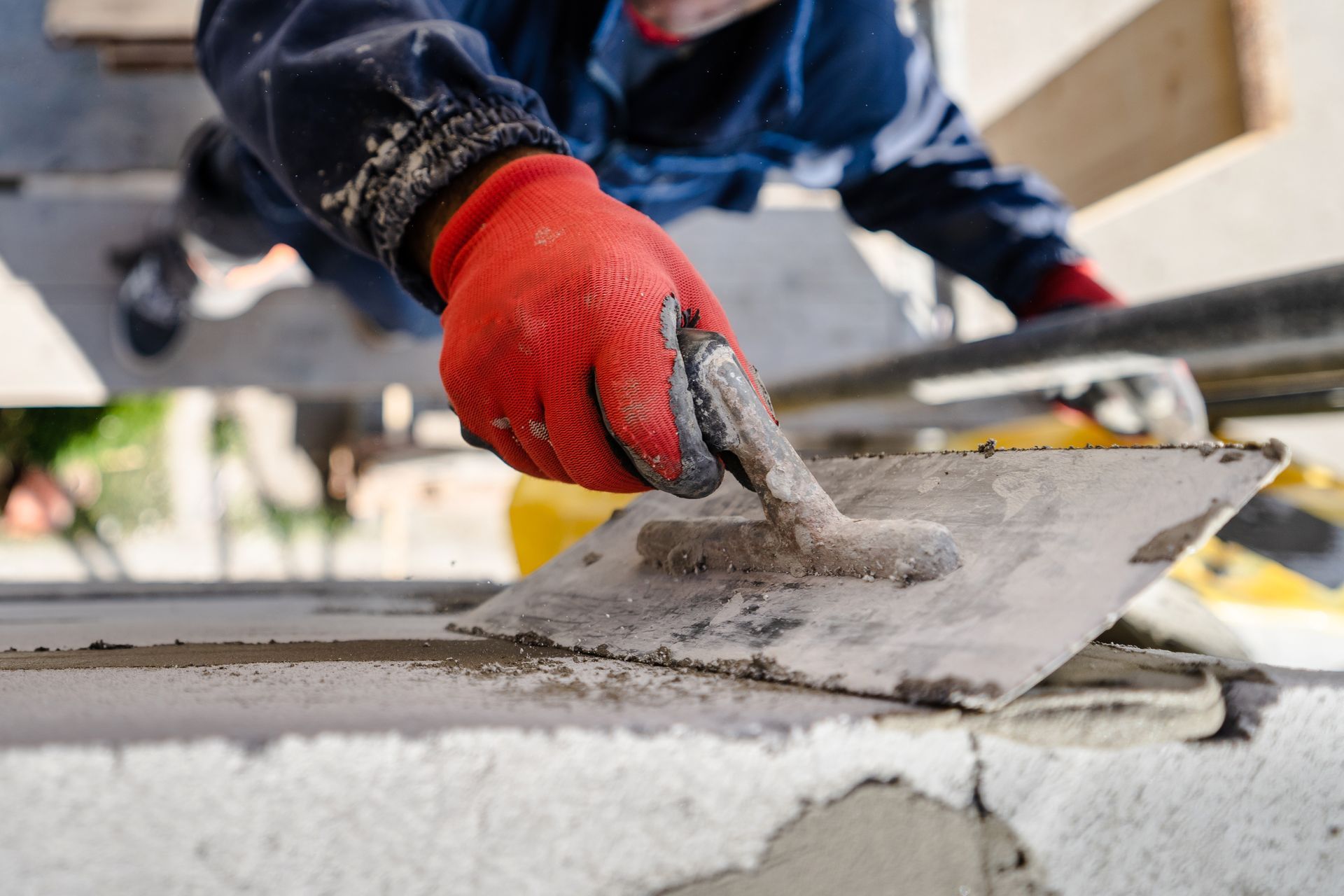 Skilled worker using a trowel for concrete finishing during a commercial remodeling project.