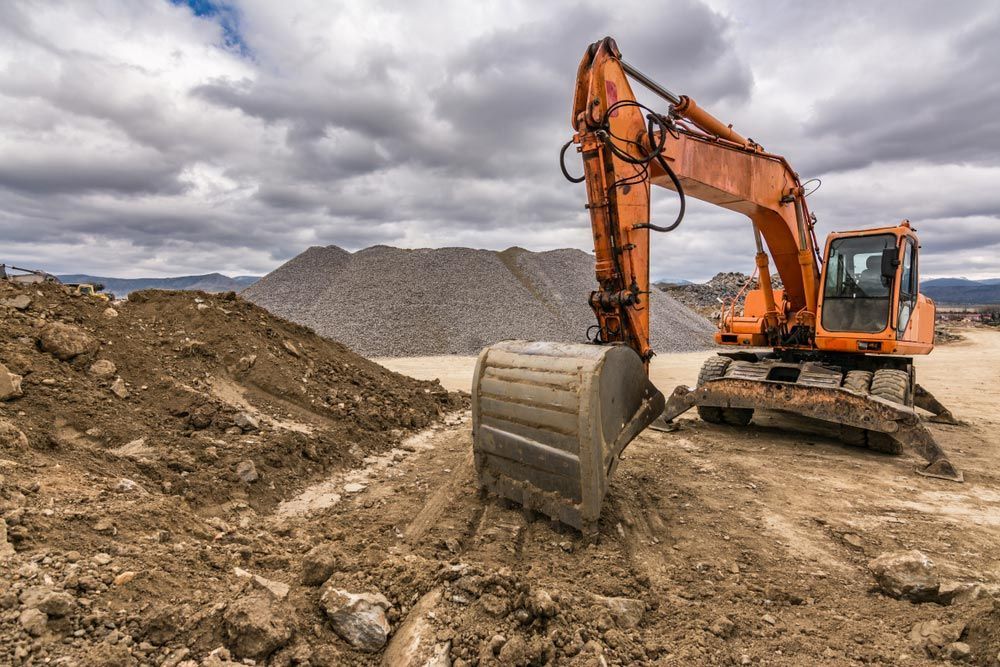 An Orange Excavator Is Digging A Hole In A Dirt Field — W Wall & Sons In Cannonvale, QLD