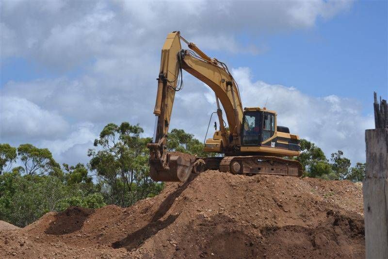 A Dump Truck Is Dumping Dirt Next To A Bulldozer — W Wall & Sons In Proserpine, QLD
