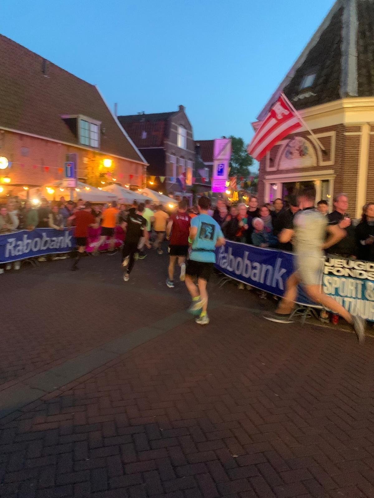 A group of people running down a street with rabobank banners