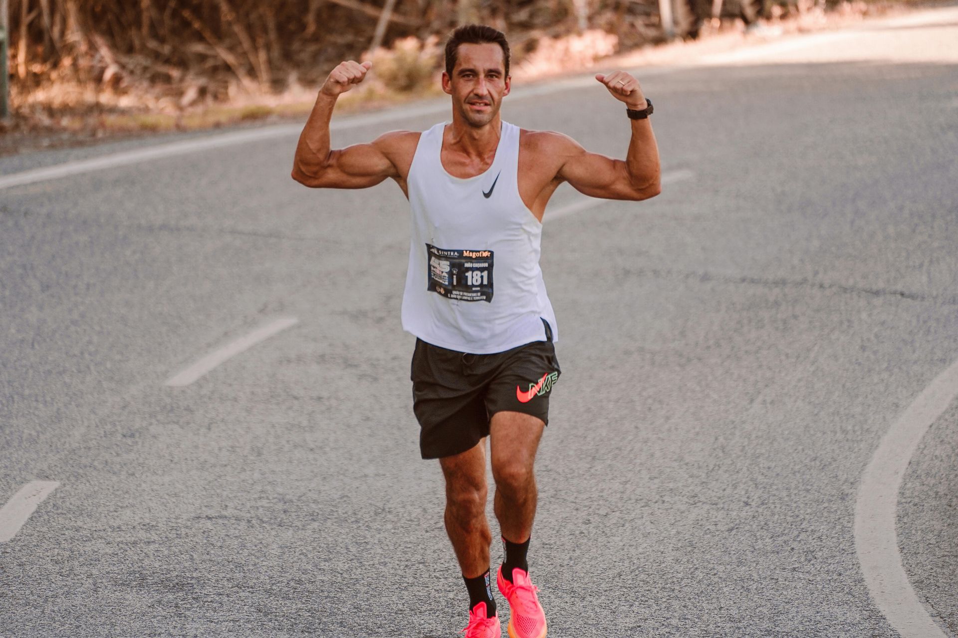 A man is running down a road with his arms outstretched.