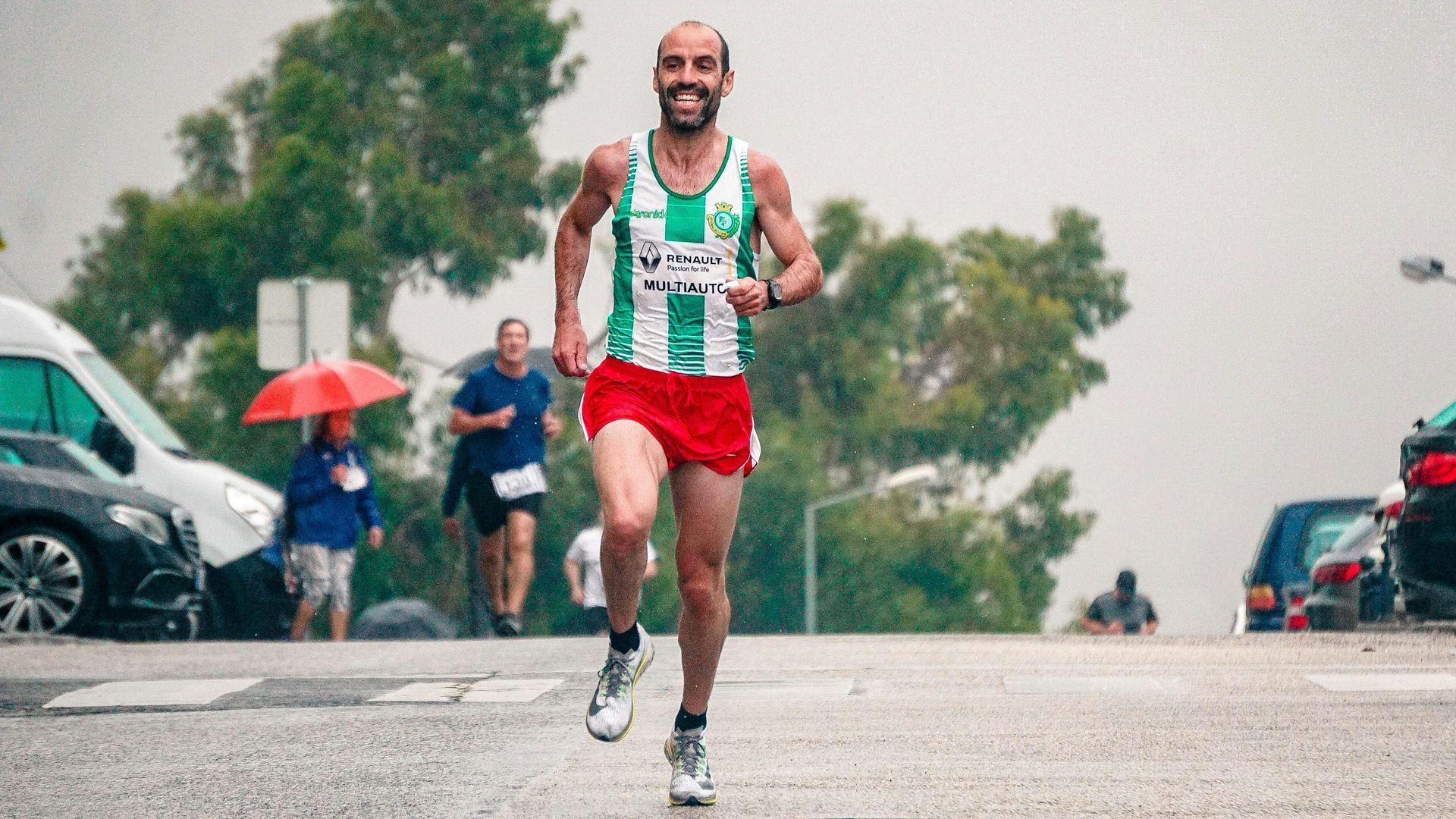 A man is running down a street in a parking lot.