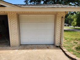 A white garage door is open on a brick building