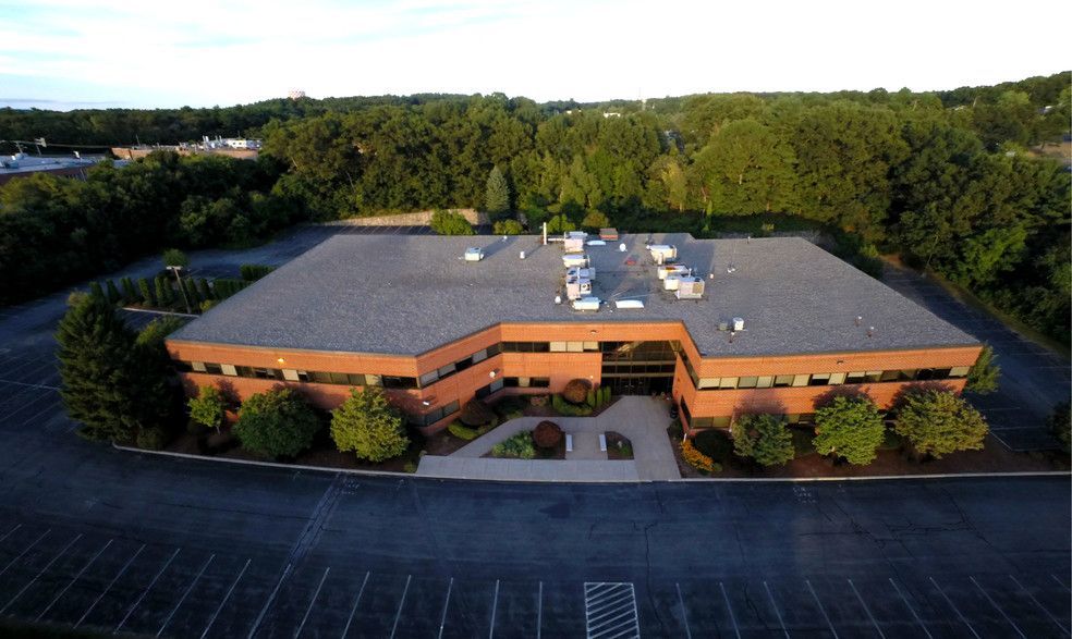 An aerial view of a large brick building with a parking lot in front of it.