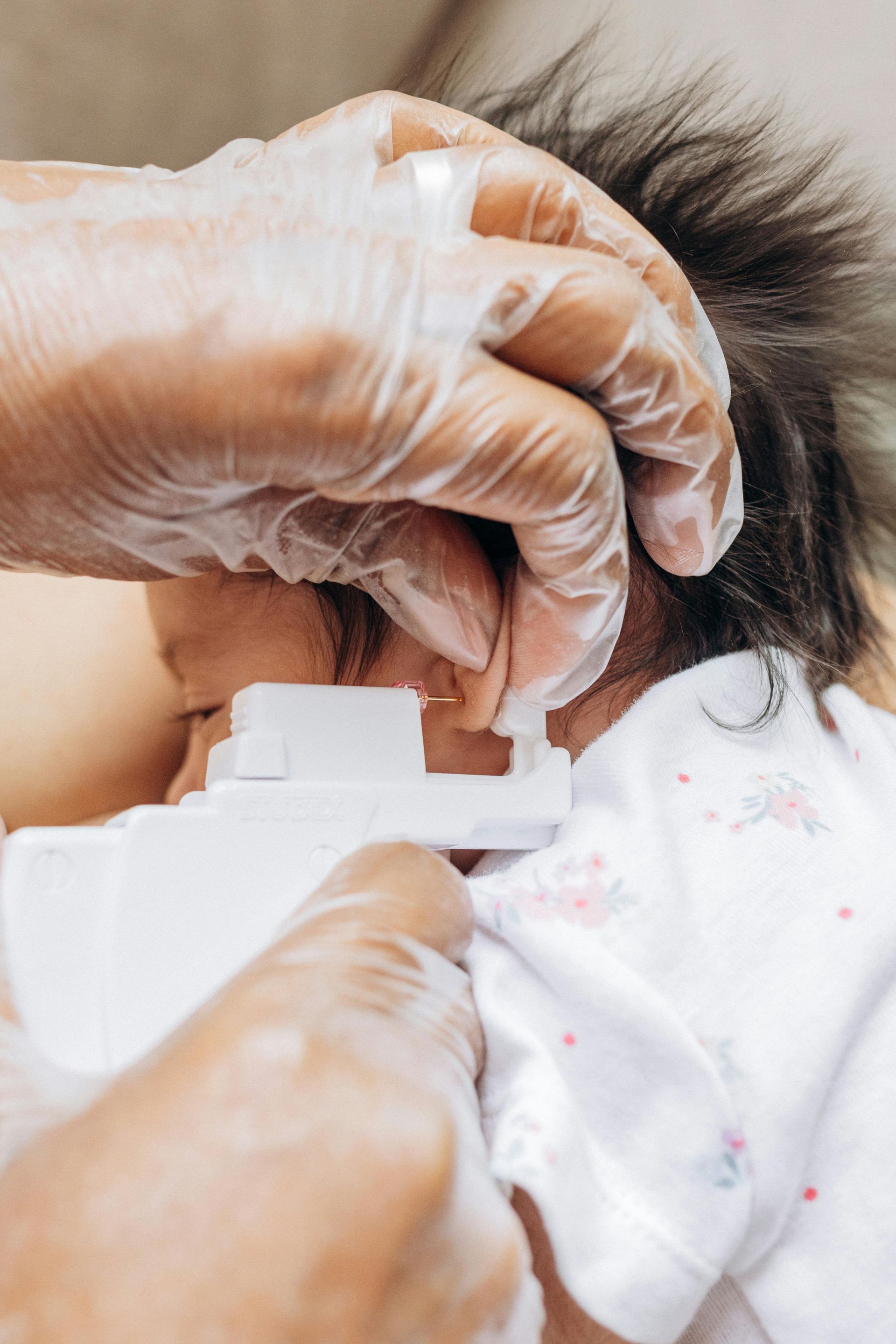 Young girl getting her ear pierced.