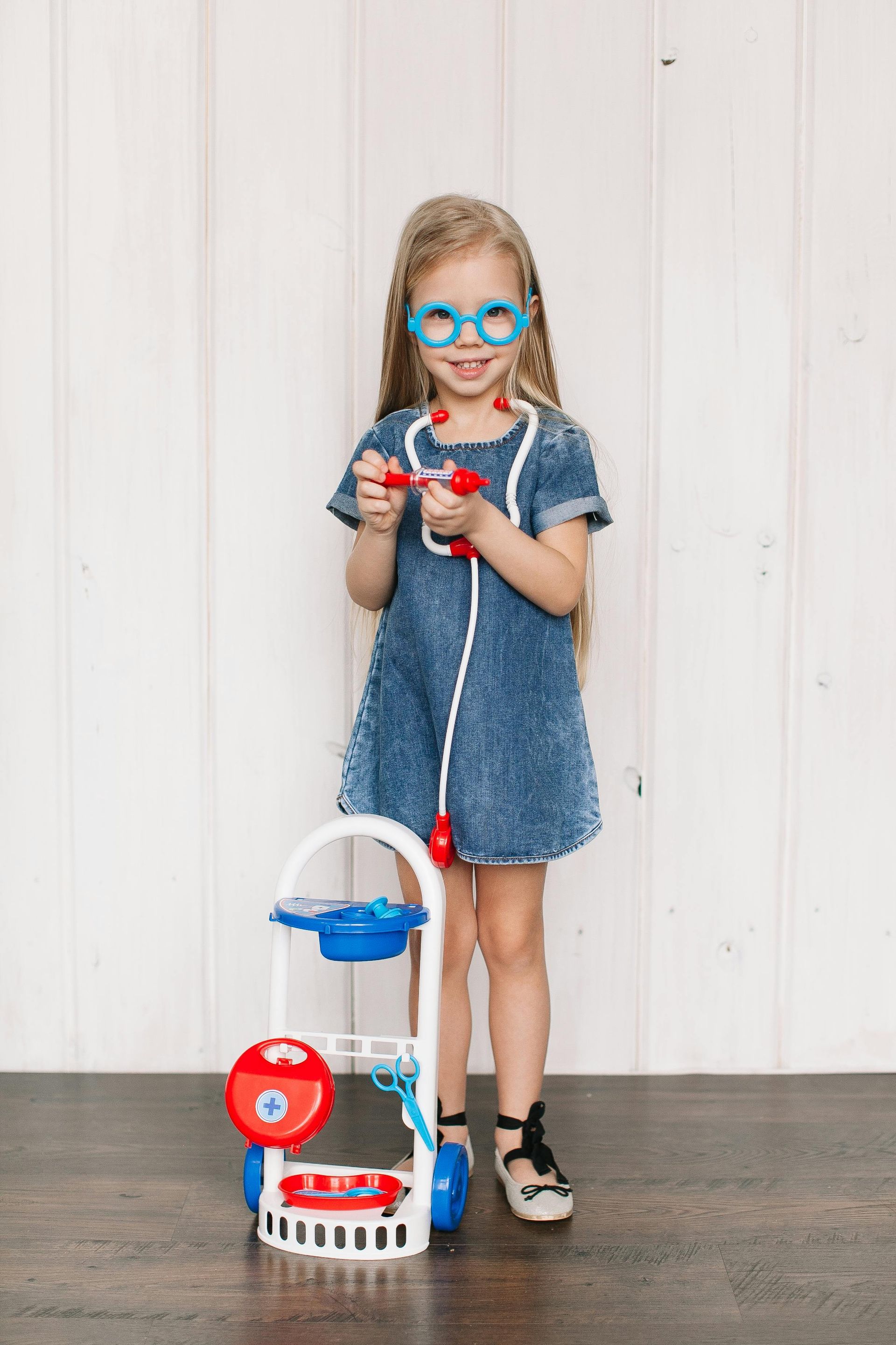 A young girl has a toy stethoscope around her neck.