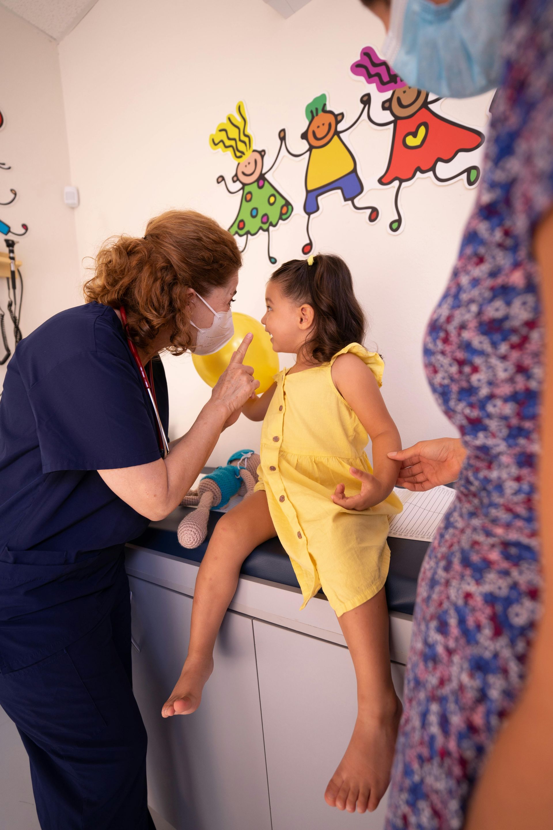 Medical professional speaking with young girl on medical table.