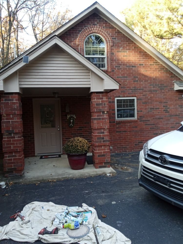 A white car is parked in front of a brick house