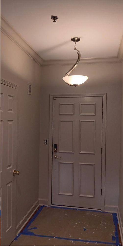 A hallway with a door and a light hanging from the ceiling.